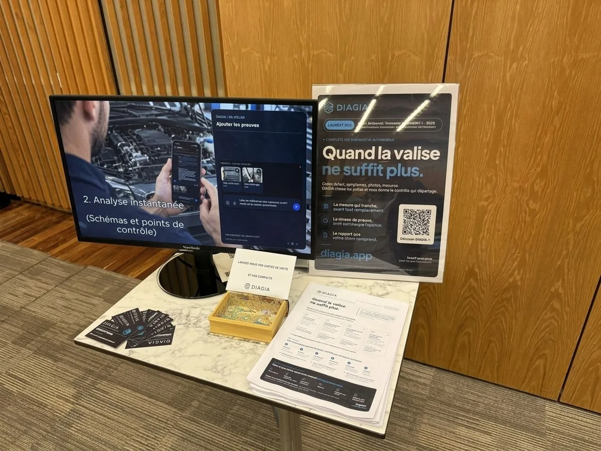 Le stand DIAGIA à Bercy le 7 octobre 2026 : écran de démonstration de l’application de diagnostic automobile par IA, affiche « Quand la valise ne suffit plus », fiches de présentation et cartes DIAGIA